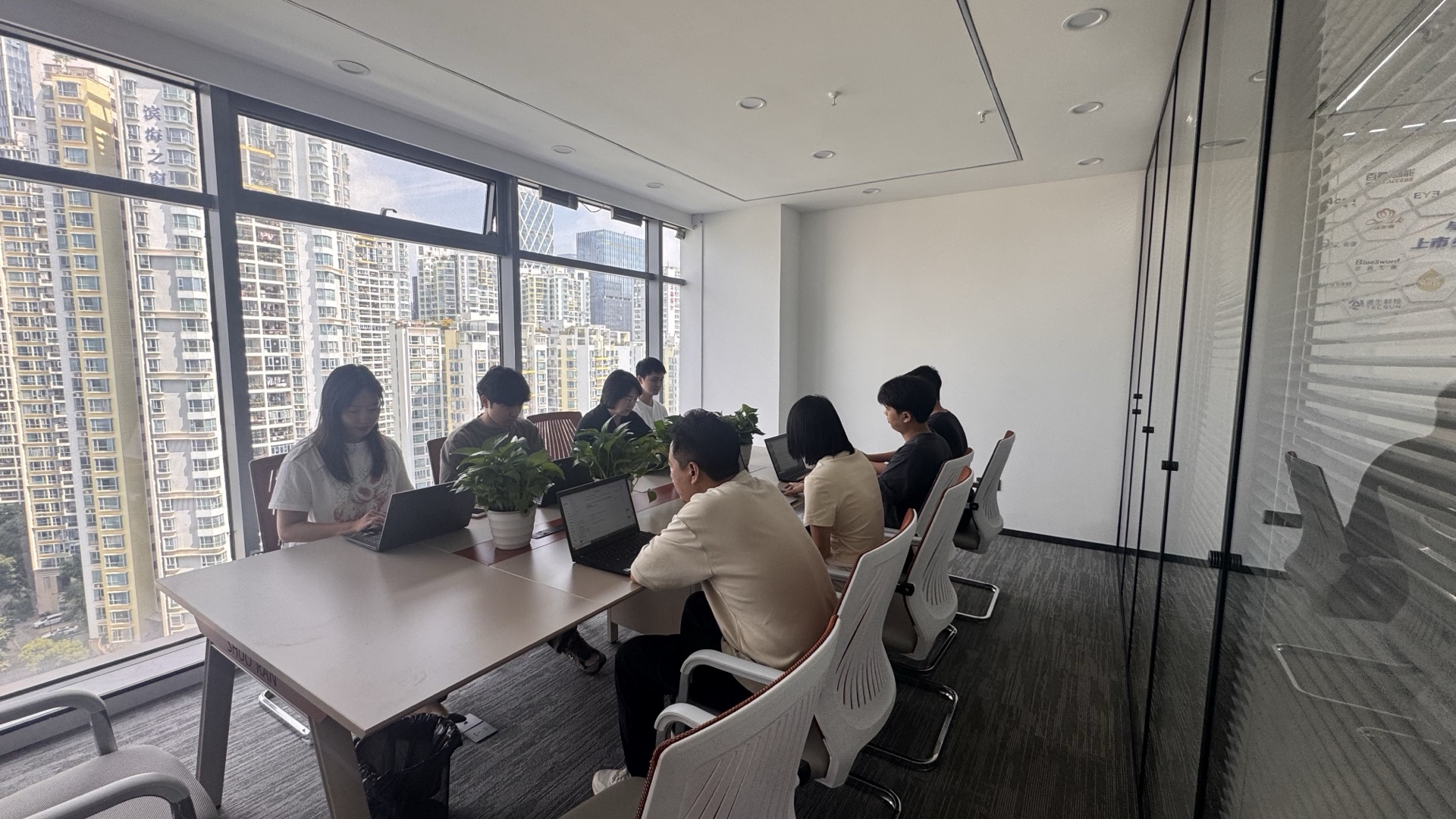 九序团队围坐在会议室长桌前讨论方案，窗外是城市景观